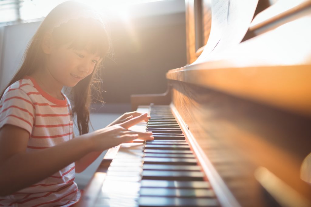 Smiling girl practicing piano in classroom